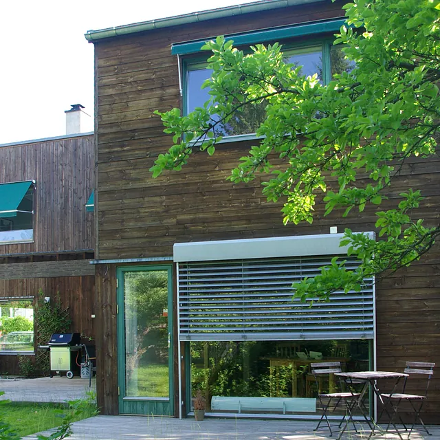 Moderne hus i mørkt tre med store vindusflater