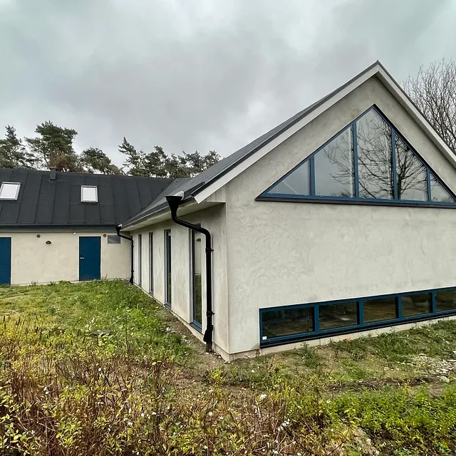 L-formet bygg med skråtak og store glassfelt